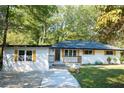 White ranch house with a gray roof, and yellow shutters, nestled in a wooded area at 1807 W Austin Rd, Decatur, GA 30032