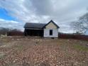 A view of the home's dilapidated rear and unkempt backyard at 7163 Swift St, Lithonia, GA 30058