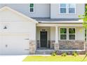 Charming home featuring a welcoming front porch, stone accents, and a two-car garage at 307 Willam Gossett Dr, Canton, GA 30114
