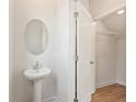 Small bathroom with pedestal sink, oval mirror, and closet at 1944 Westwind Street (Lot 133), Lawrenceville, GA 30043