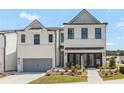 Two-story townhome with white brick exterior, gray garage door, and landscaping at 1946 Westwind Street (Lot 132), Lawrenceville, GA 30043