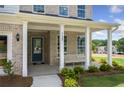 Covered front porch with white columns, a blue door, and a bench at 344 Foxglove Way, Mcdonough, GA 30253