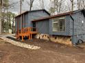 Rear exterior view of a home with a wood deck, stone accents, and freshly painted blue siding at 296 Grist Mill Ln, Lawrenceville, GA 30046