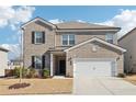 Two-story brick home with a white two-car garage and landscaped lawn at 4169 Wood Fern Ln, Buford, GA 30519