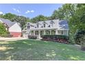 Two-story house with a wrap-around porch and landscaped yard at 5032 Hickory Hills Dr, Woodstock, GA 30188