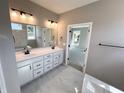 Primary bathroom with dual sinks, tile floors, framed mirror and a view into the main bedroom at 44 Easton Park Blvd, Dallas, GA 30157
