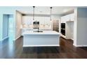 Bright kitchen features white cabinets, stainless steel appliances, a center island, and gorgeous wood floors at 44 Easton Park Blvd, Dallas, GA 30157