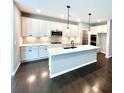 Bright kitchen features white cabinets, stainless steel appliances, a center island, and gorgeous wood floors at 44 Easton Park Blvd, Dallas, GA 30157