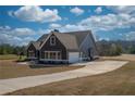 View of the gray home showcasing the attached garage, large driveway, and well-maintained lawn at 181 Woodfin Way, Social Circle, GA 30025