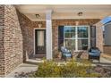 Inviting front porch with brick columns, two wicker chairs, and landscaping at 210 Omega Ct, Dallas, GA 30157