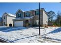 Two-story brick home with a white garage door and snowy lawn at 129 Warbler Way, Mcdonough, GA 30253