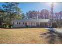 Single-story home with covered front porch and carport featuring a red front door and a sprawling yard at 2424 West Rd, Riverdale, GA 30296