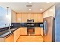 Modern kitchen boasts stainless steel appliances, wood cabinets, and black tiled backsplash at 860 Peachtree Ne St # 2506, Atlanta, GA 30308
