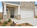 Home entrance featuring a black front door, stone pillars, and a white garage door at 602 Wallace Oak Ln, Lawrenceville, GA 30045