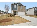 Two-story home with stone and blue siding, a two-car garage, and a tree in the front yard at 602 Wallace Oak Ln, Lawrenceville, GA 30045