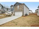 Two-story home with stone and gray siding, a two-car garage, and a driveway at 602 Wallace Oak Ln, Lawrenceville, GA 30045