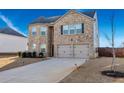 Two-story brick home with a two-car garage and landscaped yard at 909 Teabiscuit Way, Mcdonough, GA 30253
