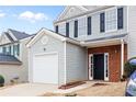Two-story townhome with gray siding, brick accents, and a white garage door at 132 Timber Mist Ln, Lawrenceville, GA 30045
