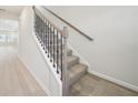 Carpeted staircase with wooden handrail and black iron balusters at 701 Lily Blossom Path Path, Lawrenceville, GA 30045