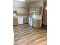 L-shaped kitchen with light cabinets, white appliances, and wood-look vinyl flooring at 114 Odyssey Turn, Conyers, GA 30012