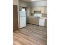 Galley kitchen with light cabinets, white appliances, and wood-look vinyl flooring at 114 Odyssey Turn, Conyers, GA 30012