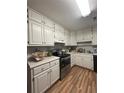 Well-lit kitchen with white cabinets, stainless steel appliances, and wood-look vinyl flooring for modern comfort at 992 Brian Ln, Forest Park, GA 30297