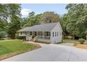 A single story house with a covered front porch surrounded by mature landscaping and a concrete driveway at 641 Virginia Ave, Suwanee, GA 30024