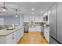 Lovely kitchen features stainless appliances, white cabinets, granite counters, pendant lighting, and hardwood floors at 641 Virginia Ave, Suwanee, GA 30024