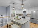 Bright kitchen features stainless appliances, white cabinets, granite counters, pendant lighting, and hardwood floors at 641 Virginia Ave, Suwanee, GA 30024