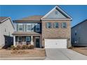 Two-story home featuring a brick facade, blue siding, gray shutters, and a two-car garage at 3346 Long Creek Dr, Buford, GA 30519