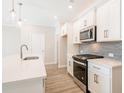 Modern kitchen with white cabinets, quartz countertops, and stainless steel appliances at 143 Bluffington Way, Marietta, GA 30066