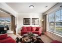 Inviting living room featuring a comfortable red sofa, stylish decor, and large windows offering ample natural light at 520 Harmony Way, Locust Grove, GA 30248