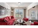 Bright living room showcasing a plush red sofa, decorative artwork, and natural light streaming through large windows at 520 Harmony Way, Locust Grove, GA 30248