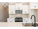 Modern kitchen features white cabinets, quartz countertops and a geometric backsplash at 701 Trevett Way, Marietta, GA 30062