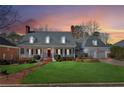 Sunset view of a charming home featuring a welcoming front porch, manicured lawn, and attached two-car garage at 1449 Brentford Cv, Snellville, GA 30078