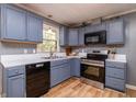 Cozy kitchen with blue cabinets, stainless steel appliances, and a window offering natural light at 1167 Mcclung Rd, Hiram, GA 30141