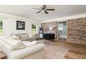 Well-lit living room with brick accent wall, hardwood floors, and view into renovated bathroom at 1167 Mcclung Rd, Hiram, GA 30141