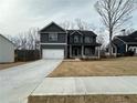 Two-story home with a two-car garage, dark gray siding, and a long driveway at 5547 Bent Grass Way, Douglasville, GA 30135