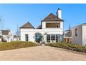 Beautiful white brick home showcasing large windows, a covered balcony, and meticulously manicured front yard under a clear sky at 230 Central Ave, Fayetteville, GA 30214