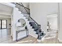 Elegant foyer showcasing a staircase with black railing, light hardwood floors and stylish decor at 5702 Brynwood Nw Cir, Acworth, GA 30101