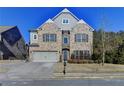 Brick two-story house with a three-car garage and landscaping at 490 La Perla Dr, Sugar Hill, GA 30518