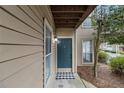 Close-up of a stylish teal front door with a checkered doormat and exterior light fixture at 2002 Country Se Dr, Smyrna, GA 30080