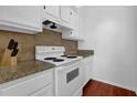 Kitchen with white cabinets and appliances, granite countertops, and backsplash at 2700 Pine Tree Ne Rd # 2306, Atlanta, GA 30324