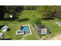 Aerial view of a fenced-in pool with a hot tub next to it, plus a colorful quilt-themed structure and treehouse at 10975 Hutcheson Ferry Rd, Chattahoochee Hills, GA 30268