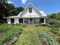 White farmhouse with a porch and lush landscaping at 10975 Hutcheson Ferry Rd, Chattahoochee Hills, GA 30268