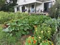 Exterior view of a lush garden filled with rows of vegetable plants and flowers near a white home with inviting front porch at 10975 Hutcheson Ferry Rd, Chattahoochee Hills, GA 30268
