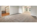 Spacious living room featuring neutral carpet and paint, adjacent to the staircase and dining area at 1019 Braelin Ct, Woodstock, GA 30189