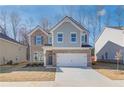Two-story brick home with gray siding, white garage door, and landscaping at 277 Tulip Dr, Covington, GA 30016