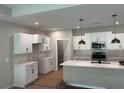 Modern kitchen with white cabinets, stainless steel appliances, pendant lighting, and a large center island awaiting finishing touches at 15 Cambridge Ln, Dallas, GA 30157