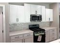 Well-lit kitchen showcasing white cabinets, stainless steel microwave, modern gas range, and stylish tile backsplash with light countertops at 15 Cambridge Ln, Dallas, GA 30157